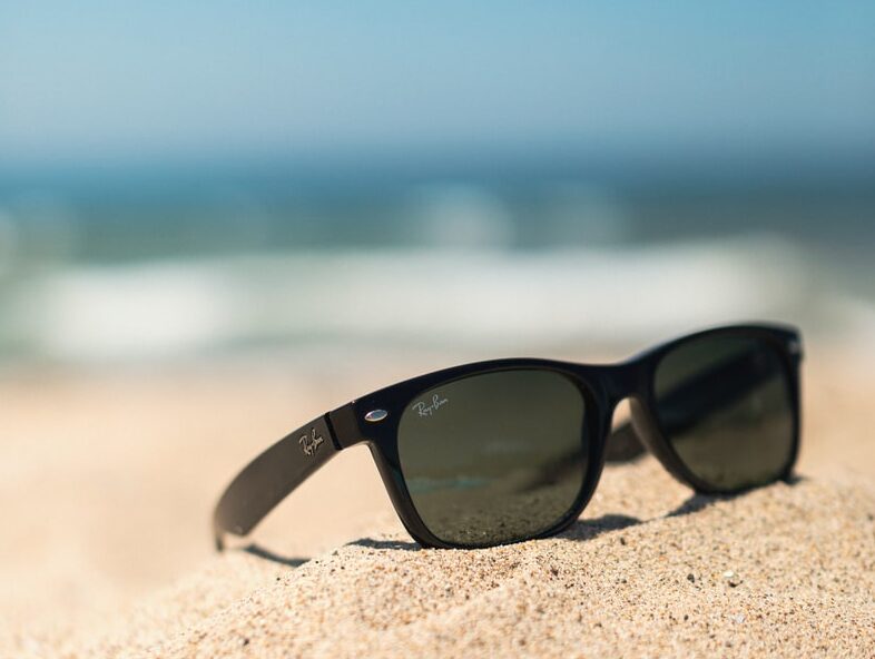black wayfarer-style sunglasses on sand
