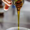 person holding clear drinking glass with brown liquid